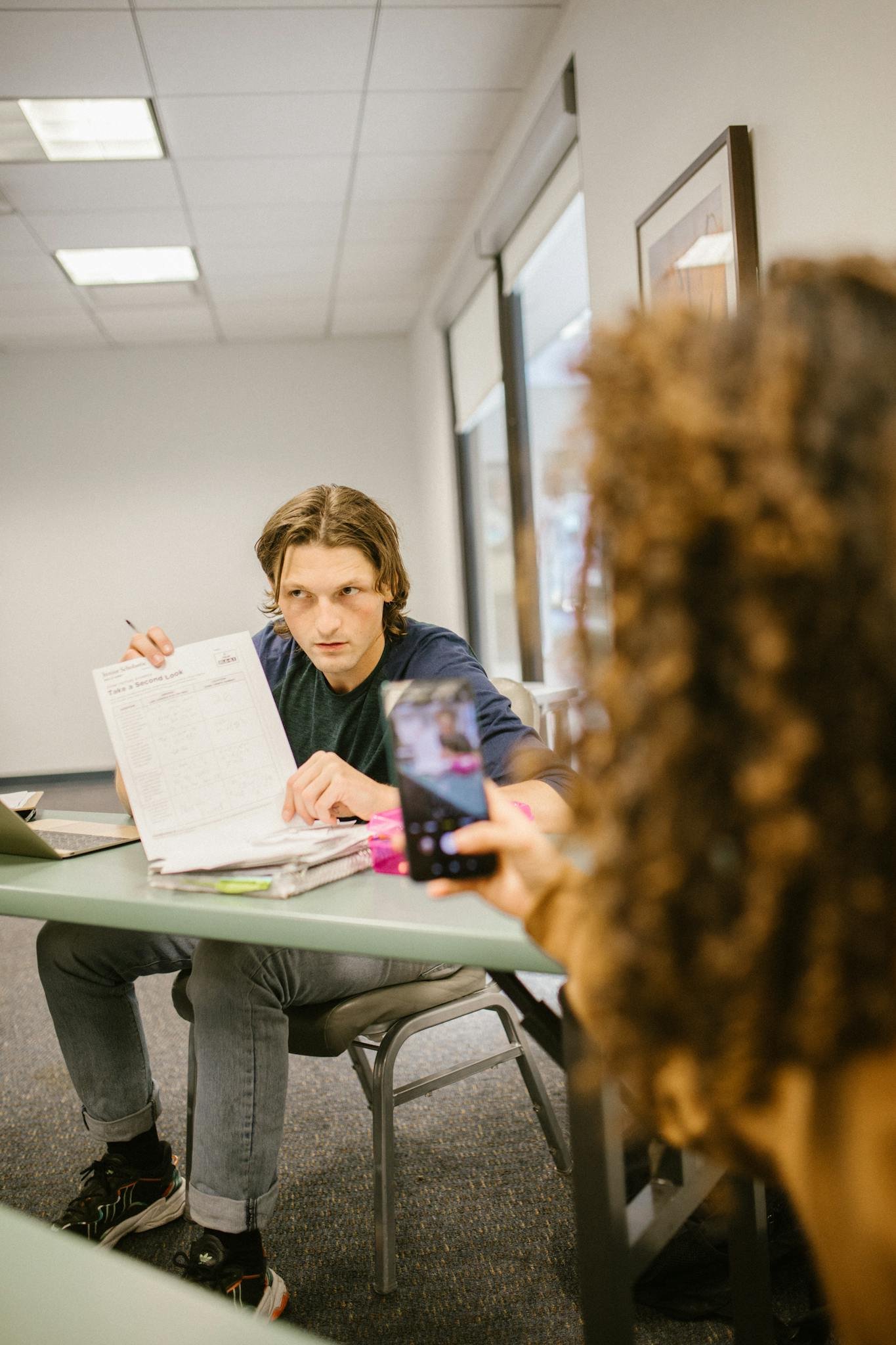 A student discreetly shares notes using a smartphone in a classroom environment.